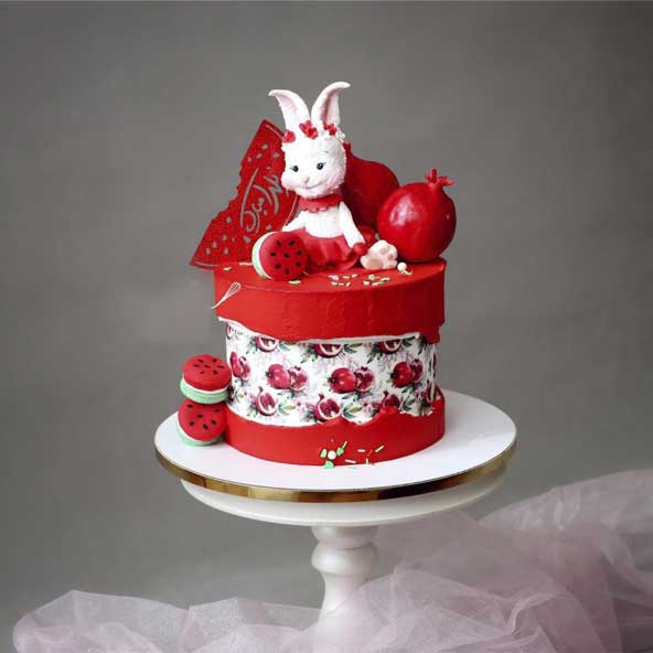کیک یک طبقه پر از خامه گرد بامزه که با تاپر خرگوش و انار و بیسکوییت هندوانه ای دیزاین شده